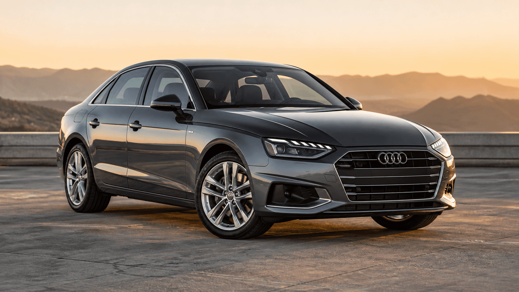 Audi A4 B9 gris oscuro en una carretera elevada al amanecer