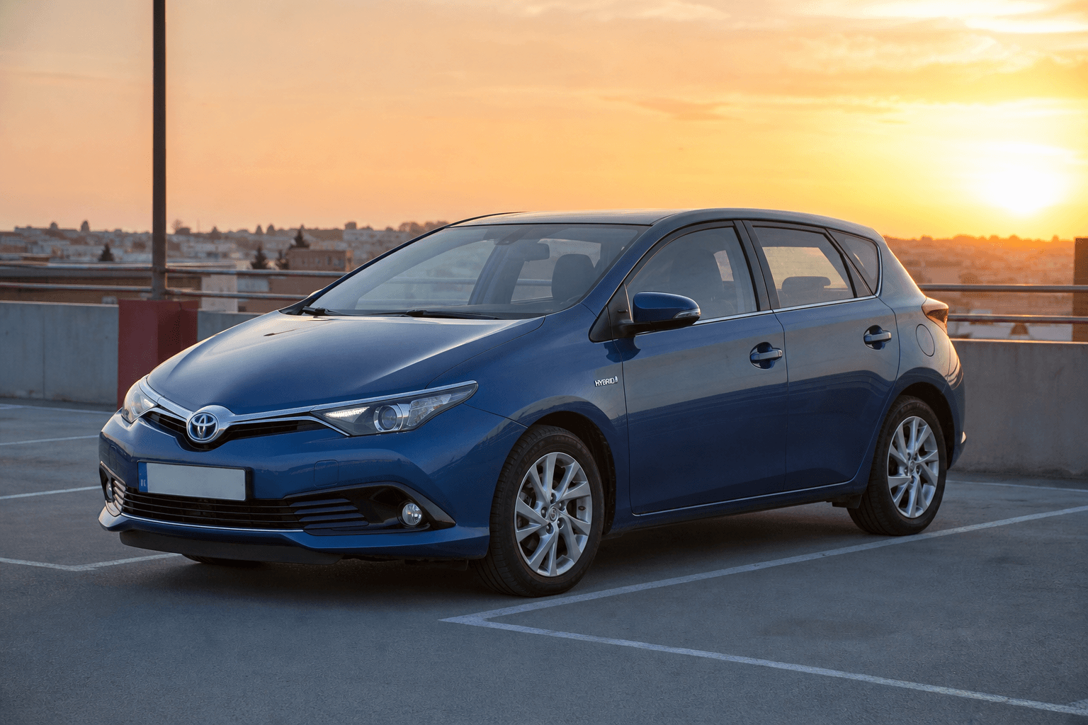 Toyota Auris E180 Hybrid azul en parking al atardecer