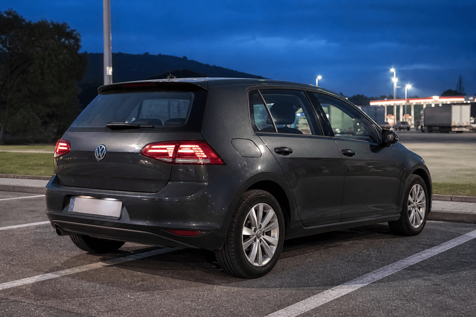 Volkswagen Golf VII gris en area de servicio al anochecer